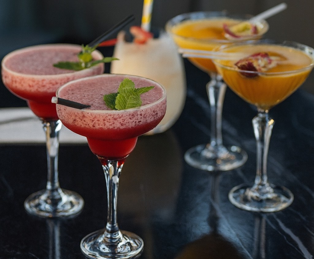 A flight of four cocktails — two daiquiris, a piña colada and two pornstar martinis